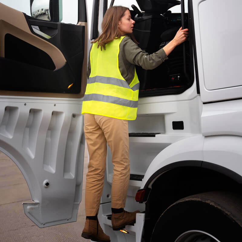 Conductrice montant dans la cabine d’un camion en gardant trois points d’appui