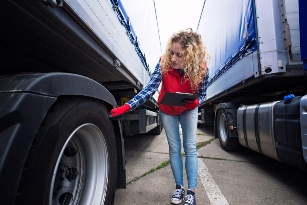 Conductrice poids lourd inspectant les pneus de son camion avant de prendre la route