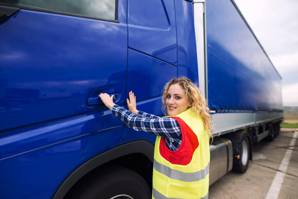 Conductrice poids lourd ouvrant la porte de la cabine de son camion