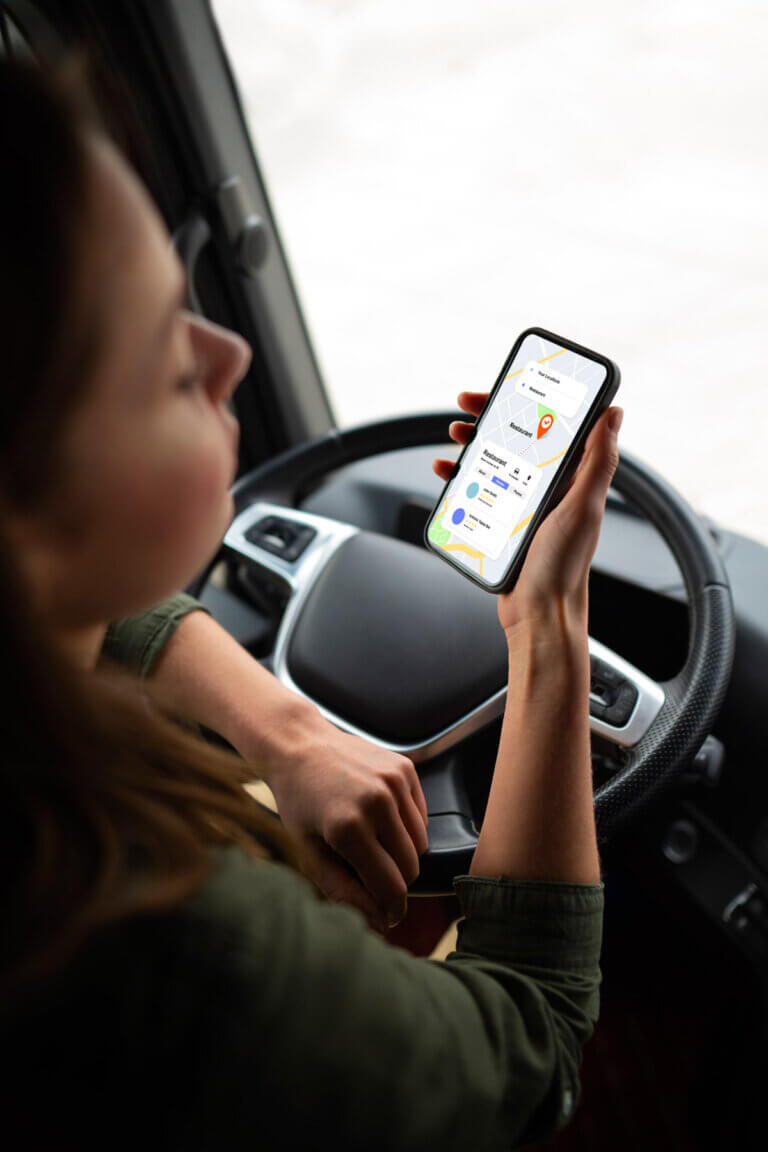 Conductrice tenant son téléphone en main au volant d’un camion
