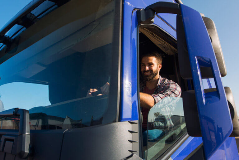Chauffeur de camion souriant à la portière de sa cabine