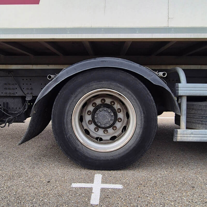 Roue de camion sur la piste d’examen du permis poids lourd, à côté d’un repère au sol